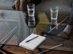 Close-up of a counseling session with two glasses of water and a notepad on a glass table.